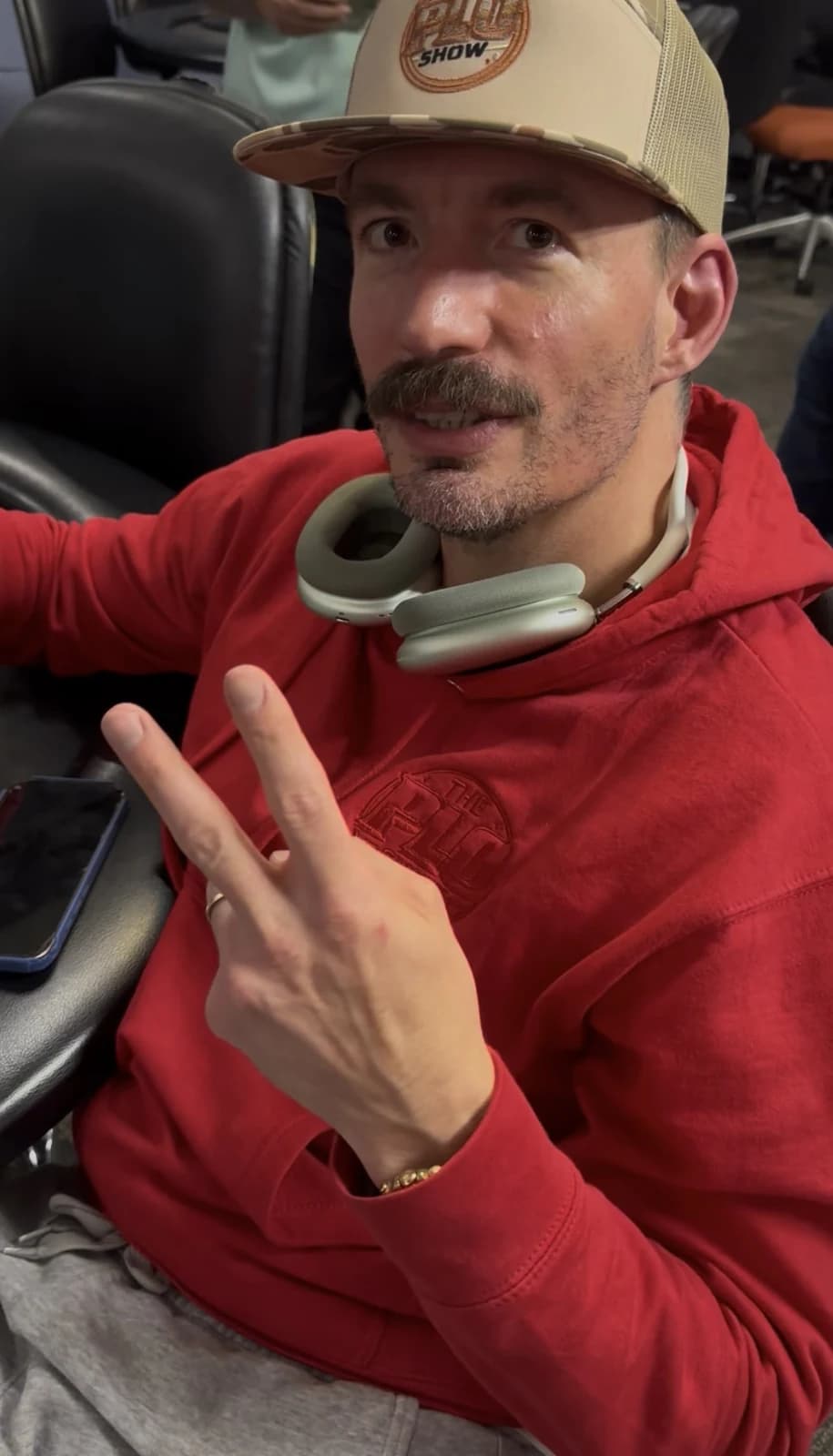 PLO Show fan in the crimson hoodie and trucker hat throwing a peace sign